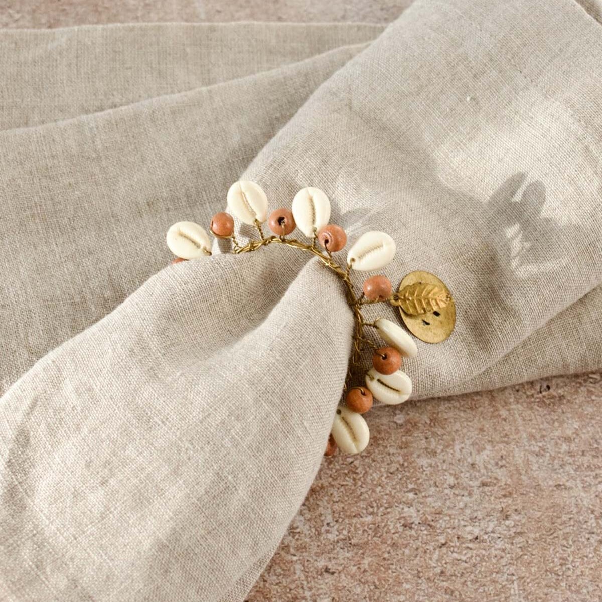 Handgemaakte servetring van De Weldaad met houten kralen en schelpjes