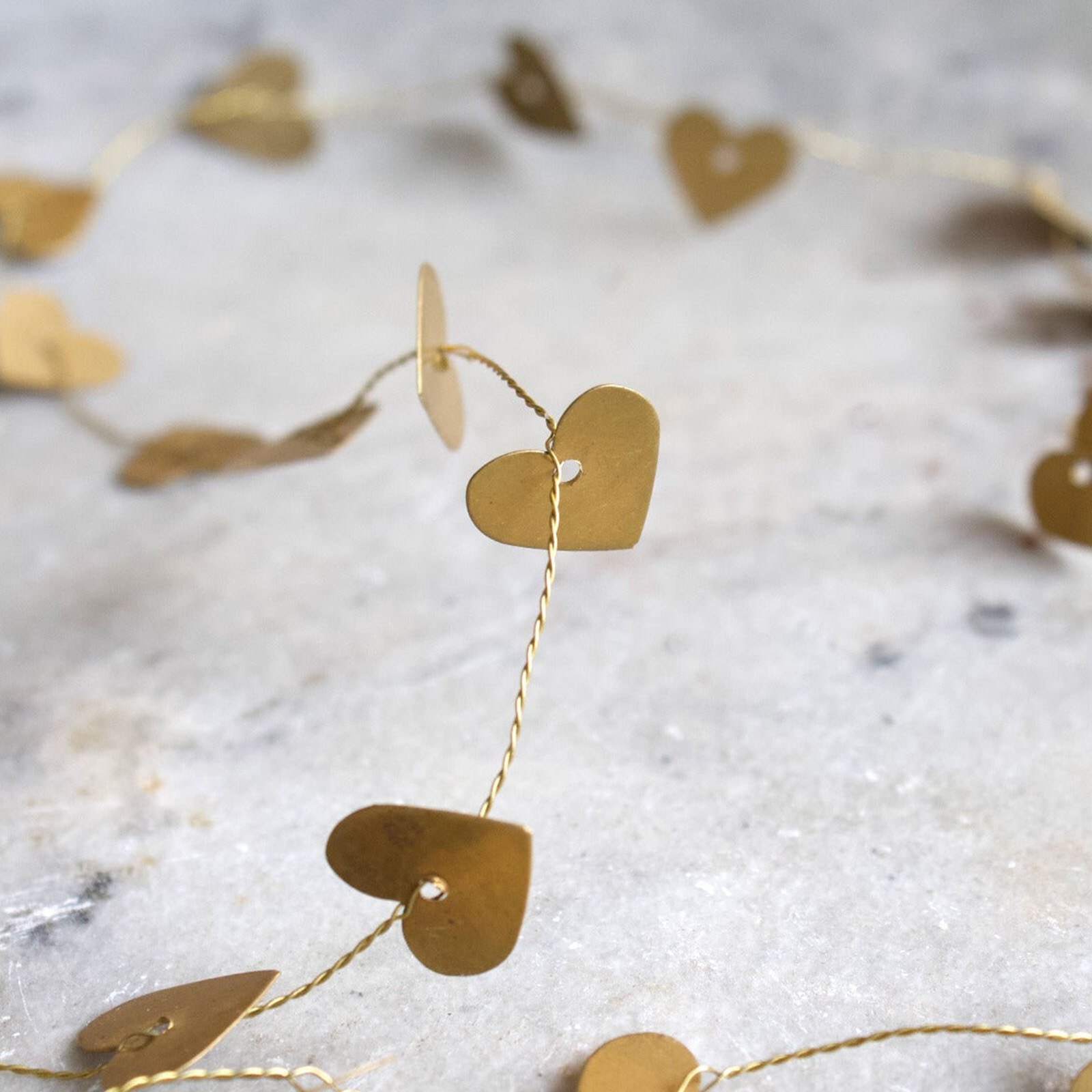 Handgemaakte gouden slinger van De Weldaad met kleine hartjes